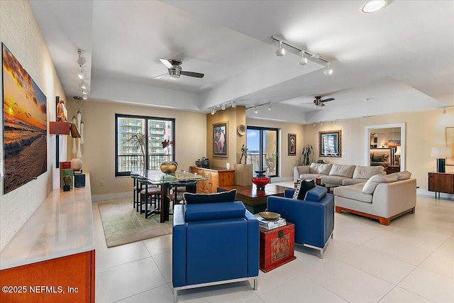 living room featuring light tile patterned floors, a tray ceiling, and ceiling fan