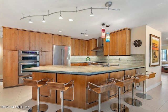 kitchen with appliances with stainless steel finishes, light tile patterned floors, decorative light fixtures, kitchen peninsula, and backsplash