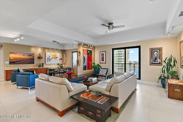 tiled living room featuring ceiling fan and a tray ceiling