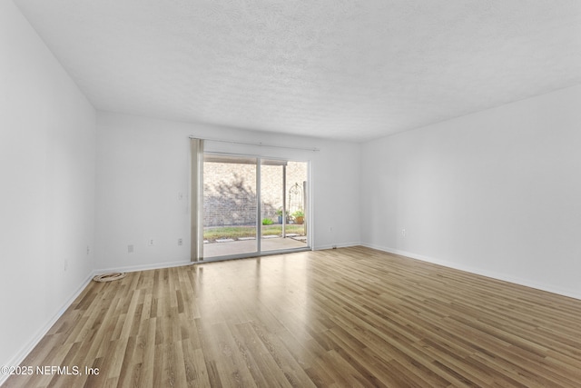 spare room with a textured ceiling and light hardwood / wood-style flooring