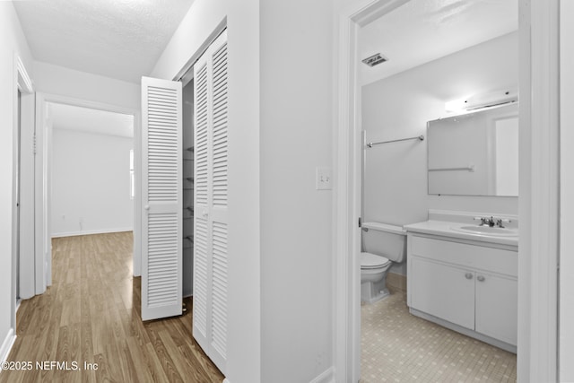 hall featuring sink, a textured ceiling, and light hardwood / wood-style floors