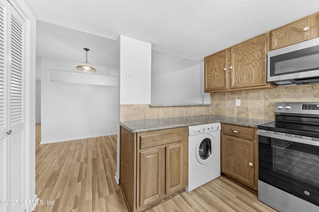 kitchen featuring decorative light fixtures, washer / dryer, decorative backsplash, light hardwood / wood-style flooring, and stainless steel appliances