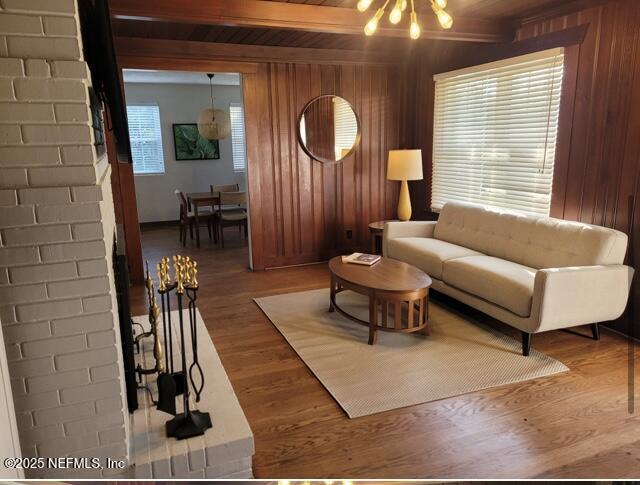 living room with wooden walls, beamed ceiling, hardwood / wood-style floors, a chandelier, and wood ceiling