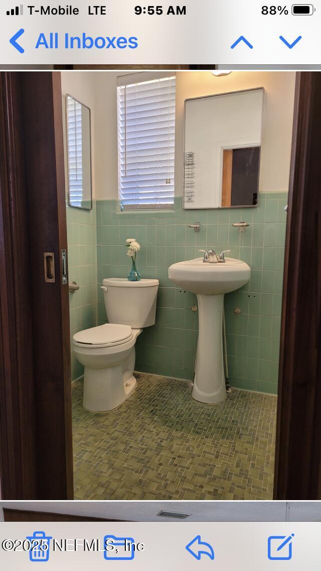 bathroom with toilet, tile patterned flooring, and tile walls