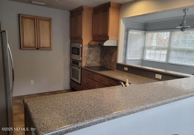 kitchen with kitchen peninsula, stainless steel appliances, tasteful backsplash, ornamental molding, and ceiling fan