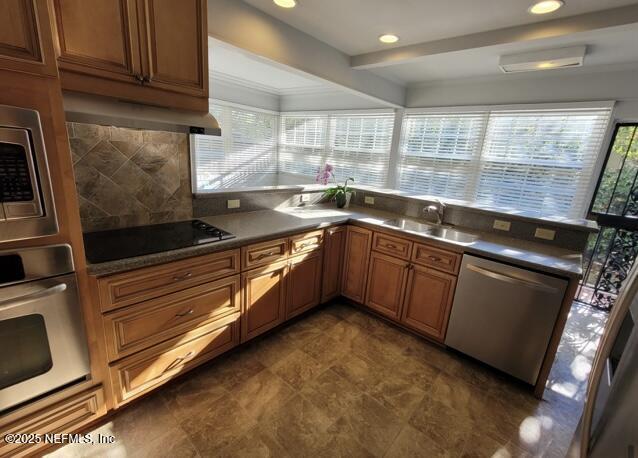 kitchen featuring tasteful backsplash, appliances with stainless steel finishes, extractor fan, and sink