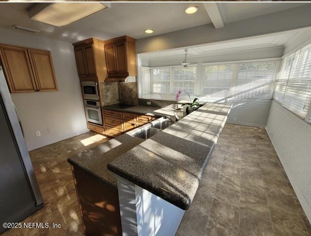 kitchen with sink, beamed ceiling, decorative backsplash, hanging light fixtures, and appliances with stainless steel finishes