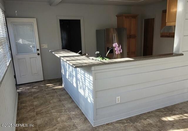 kitchen featuring beamed ceiling, kitchen peninsula, and stainless steel fridge