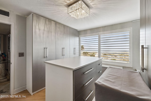 walk in closet featuring a chandelier and light hardwood / wood-style flooring