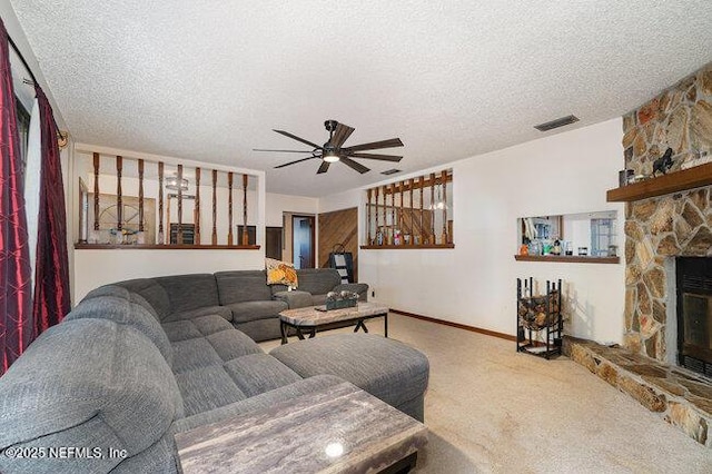 living room with ceiling fan, carpet flooring, a stone fireplace, and a textured ceiling