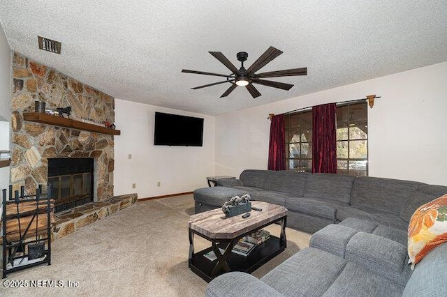 carpeted living room featuring ceiling fan, a stone fireplace, and a textured ceiling