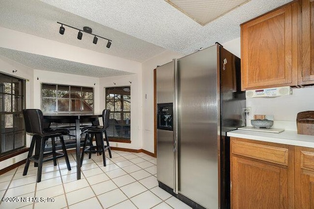 kitchen with stainless steel refrigerator with ice dispenser, light tile patterned flooring, and a textured ceiling