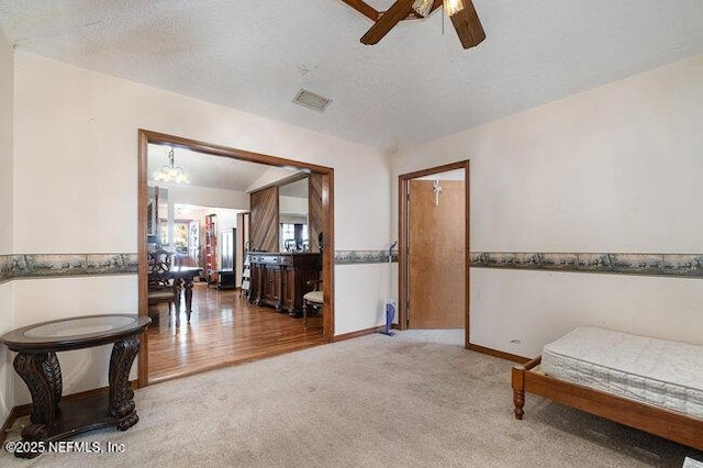 living area featuring carpet, ceiling fan with notable chandelier, and a textured ceiling