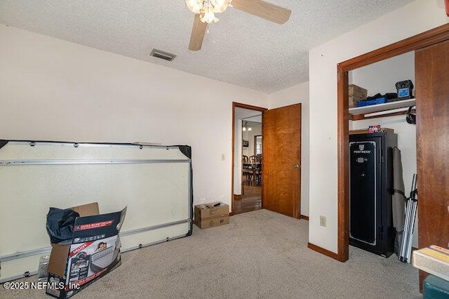 carpeted bedroom with ceiling fan and a textured ceiling