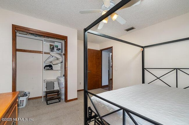 carpeted bedroom with ceiling fan, a closet, and a textured ceiling