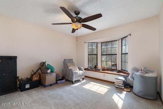 sitting room featuring ceiling fan, light colored carpet, and a textured ceiling