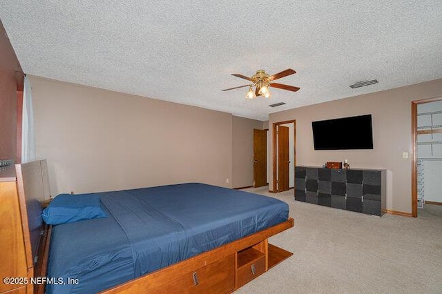 bedroom with ceiling fan, light carpet, and a textured ceiling