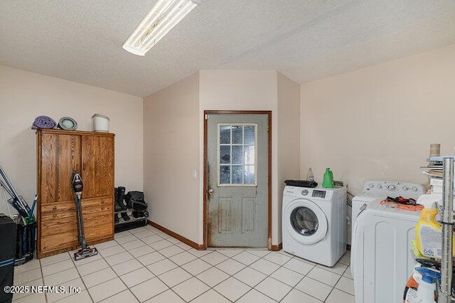 clothes washing area with independent washer and dryer, a textured ceiling, and light tile patterned floors