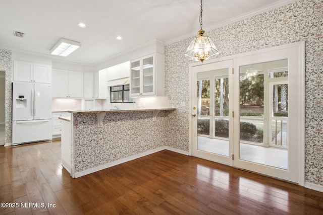 kitchen featuring pendant lighting, white cabinetry, dark hardwood / wood-style flooring, white refrigerator with ice dispenser, and kitchen peninsula