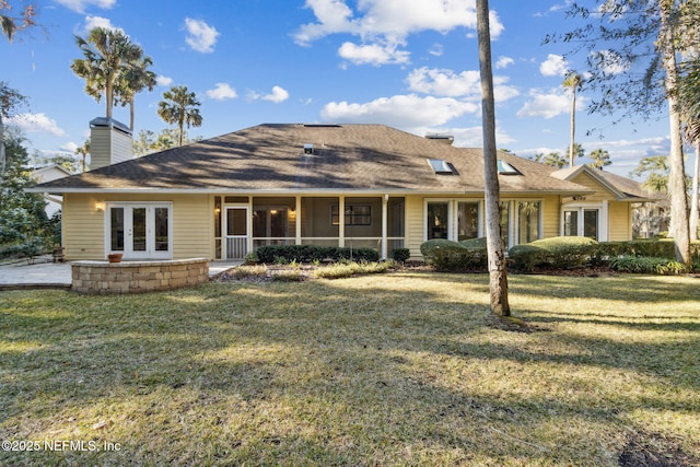 rear view of house featuring a sunroom, a yard, and french doors