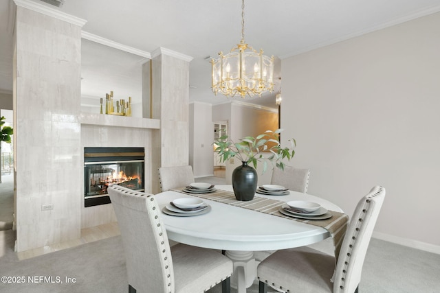 dining space featuring a fireplace, crown molding, a notable chandelier, light colored carpet, and baseboards