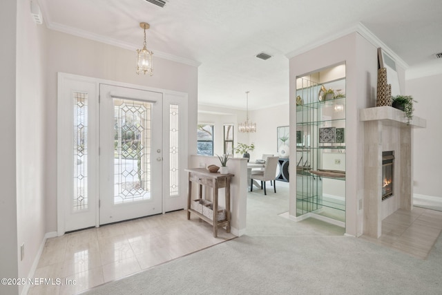 foyer featuring ornamental molding, light colored carpet, visible vents, and an inviting chandelier