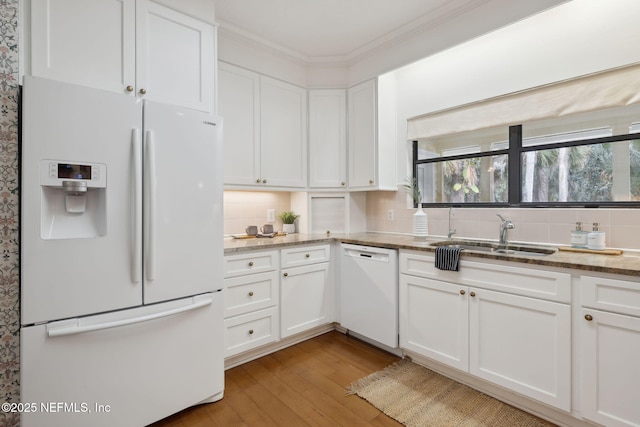 kitchen with white appliances, white cabinets, and a sink