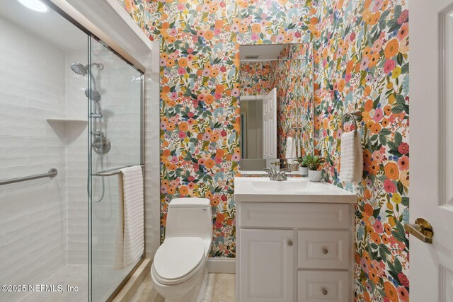 full bathroom featuring wallpapered walls, a stall shower, baseboards, toilet, and vanity