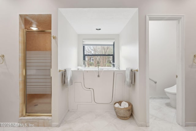 bathroom featuring toilet, a stall shower, and baseboards