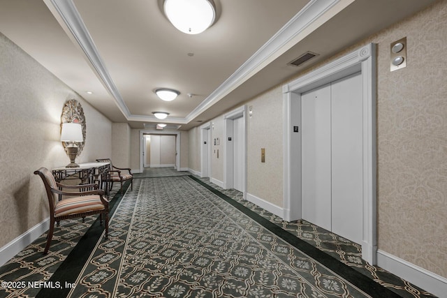 corridor with crown molding, a tray ceiling, and elevator