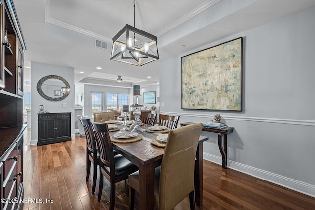 dining room featuring a raised ceiling, crown molding, hardwood / wood-style floors, and an inviting chandelier