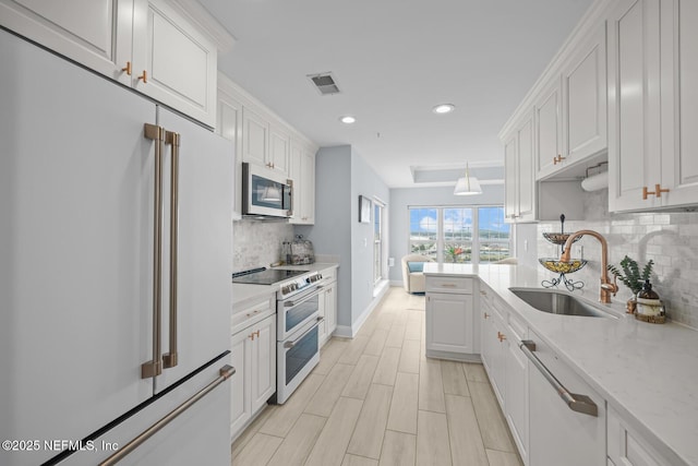 kitchen with sink, decorative light fixtures, white appliances, light stone countertops, and white cabinets