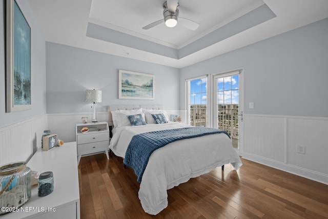 bedroom with dark wood-type flooring, access to exterior, and a tray ceiling