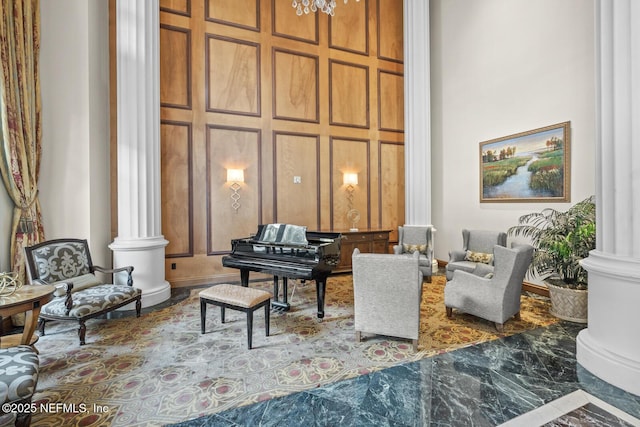 sitting room featuring decorative columns and a high ceiling