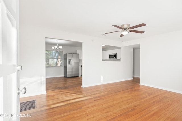 unfurnished living room with ceiling fan with notable chandelier and hardwood / wood-style floors