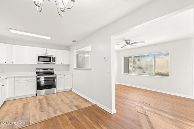 kitchen featuring ceiling fan with notable chandelier, white cabinetry, light wood-type flooring, and appliances with stainless steel finishes