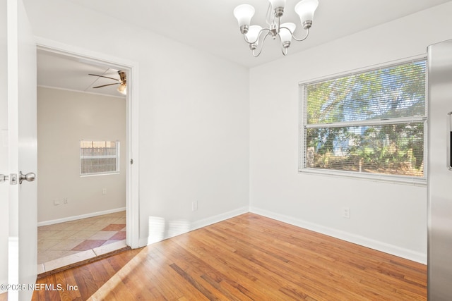 empty room featuring ceiling fan with notable chandelier and hardwood / wood-style flooring