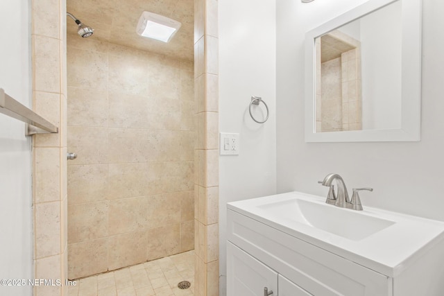 bathroom featuring tiled shower and vanity