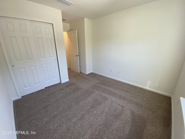 unfurnished bedroom with a closet and dark colored carpet