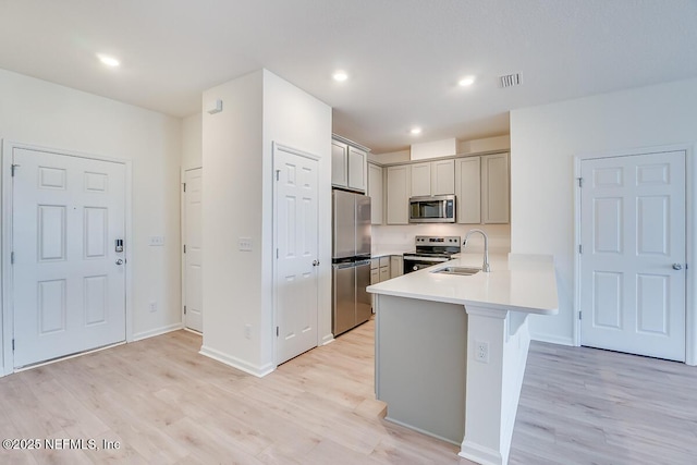 kitchen with sink, stainless steel appliances, kitchen peninsula, and light wood-type flooring