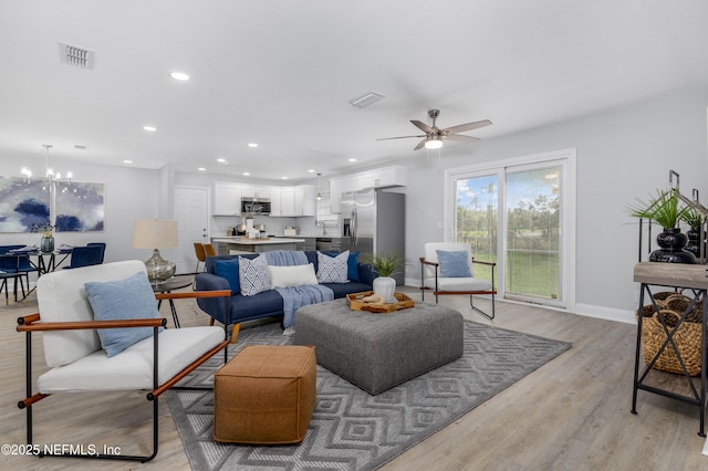 living room featuring recessed lighting, visible vents, baseboards, light wood-style flooring, and ceiling fan with notable chandelier