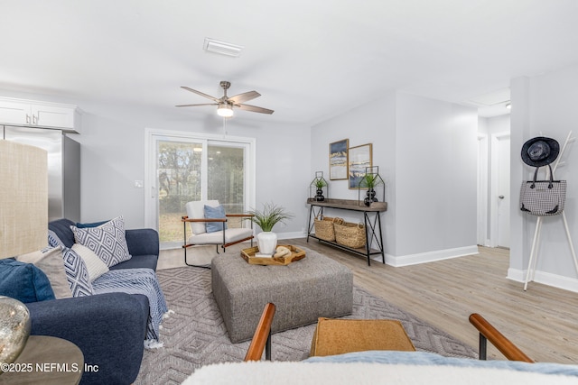 living area with baseboards, light wood finished floors, visible vents, and a ceiling fan