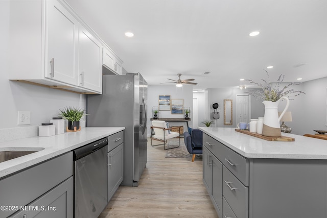 kitchen with light wood-style floors, recessed lighting, stainless steel dishwasher, and gray cabinetry