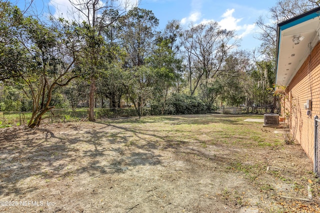 view of yard with central AC and fence