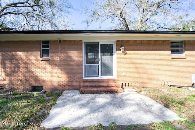 view of exterior entry featuring crawl space and brick siding