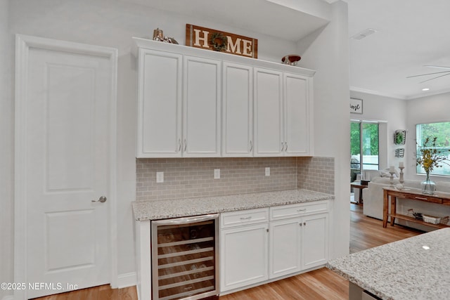 kitchen featuring white cabinetry, light stone counters, light hardwood / wood-style floors, and wine cooler