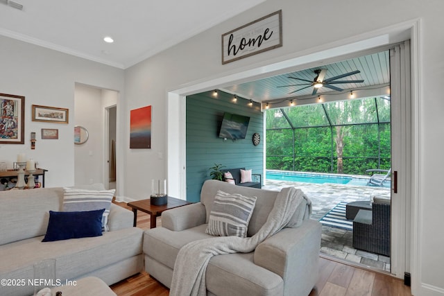 living room with wooden walls, ceiling fan, ornamental molding, and light hardwood / wood-style flooring