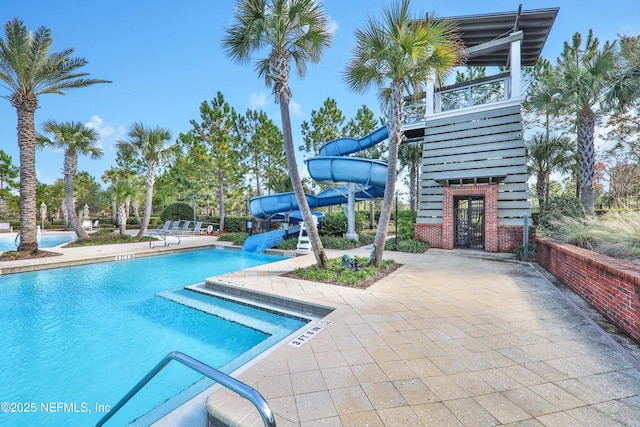 view of swimming pool with a water slide and a patio