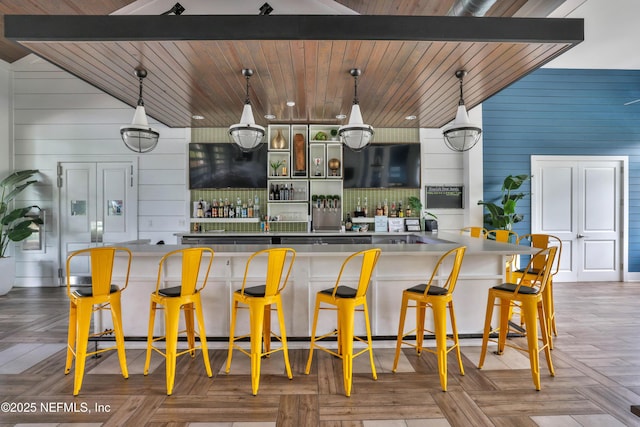 bar featuring wooden ceiling, wood walls, parquet floors, and hanging light fixtures