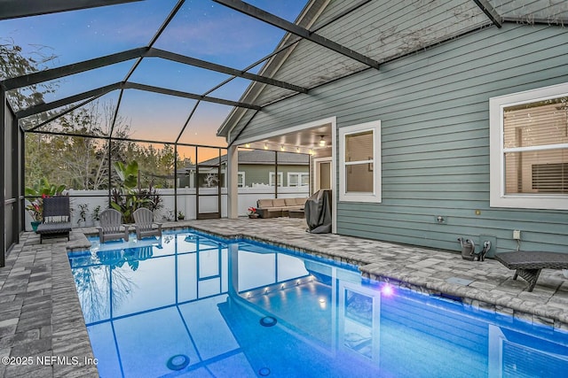 pool at dusk with a patio, glass enclosure, and outdoor lounge area